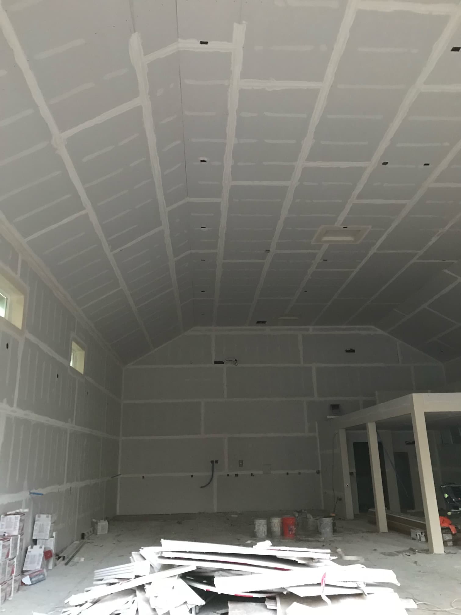 Interior room under construction with taped drywall seams on the walls and vaulted ceiling.