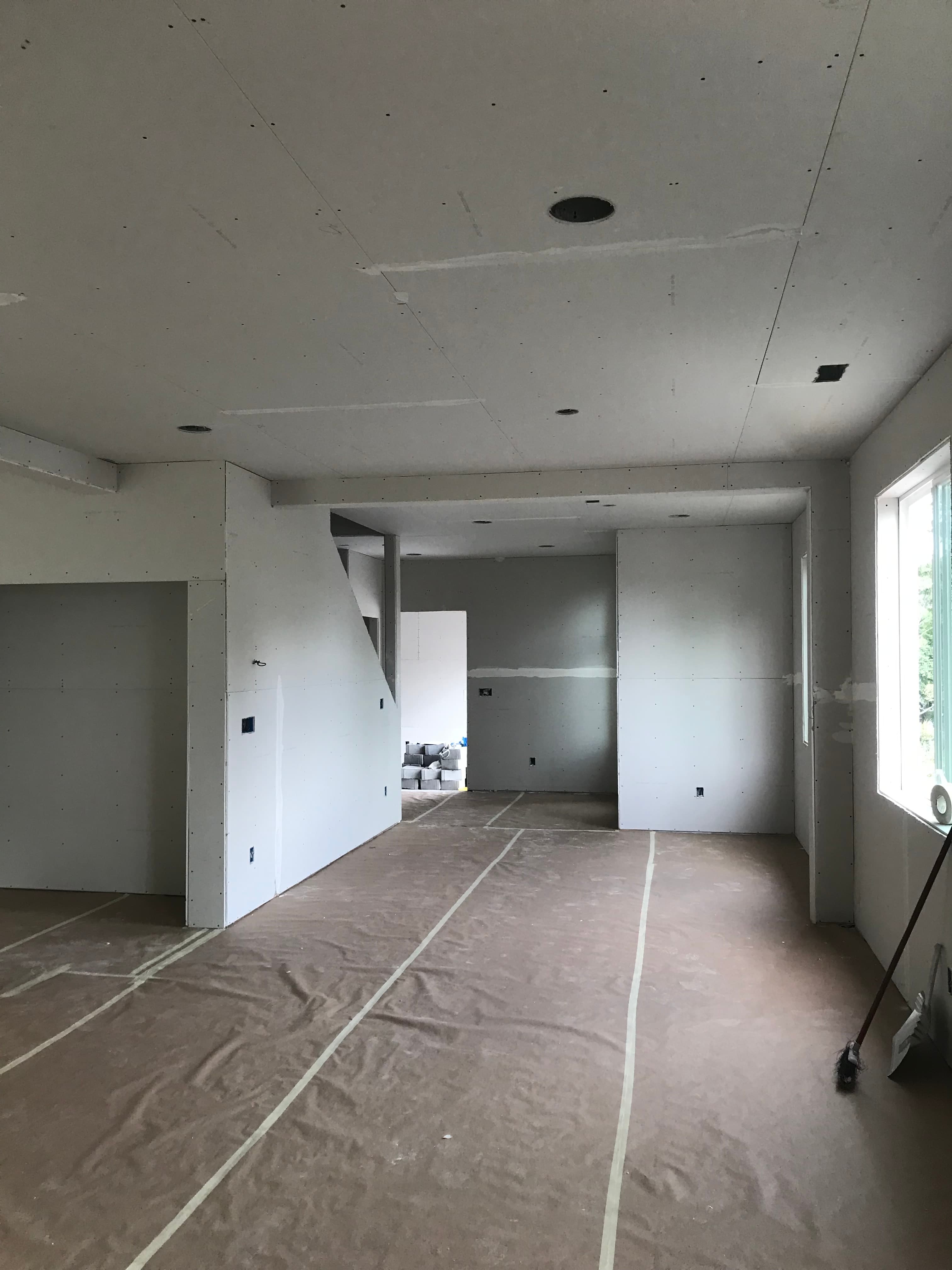 Unfinished room with installed drywall, brown paper floor protection, and a bright overhead skylight.
