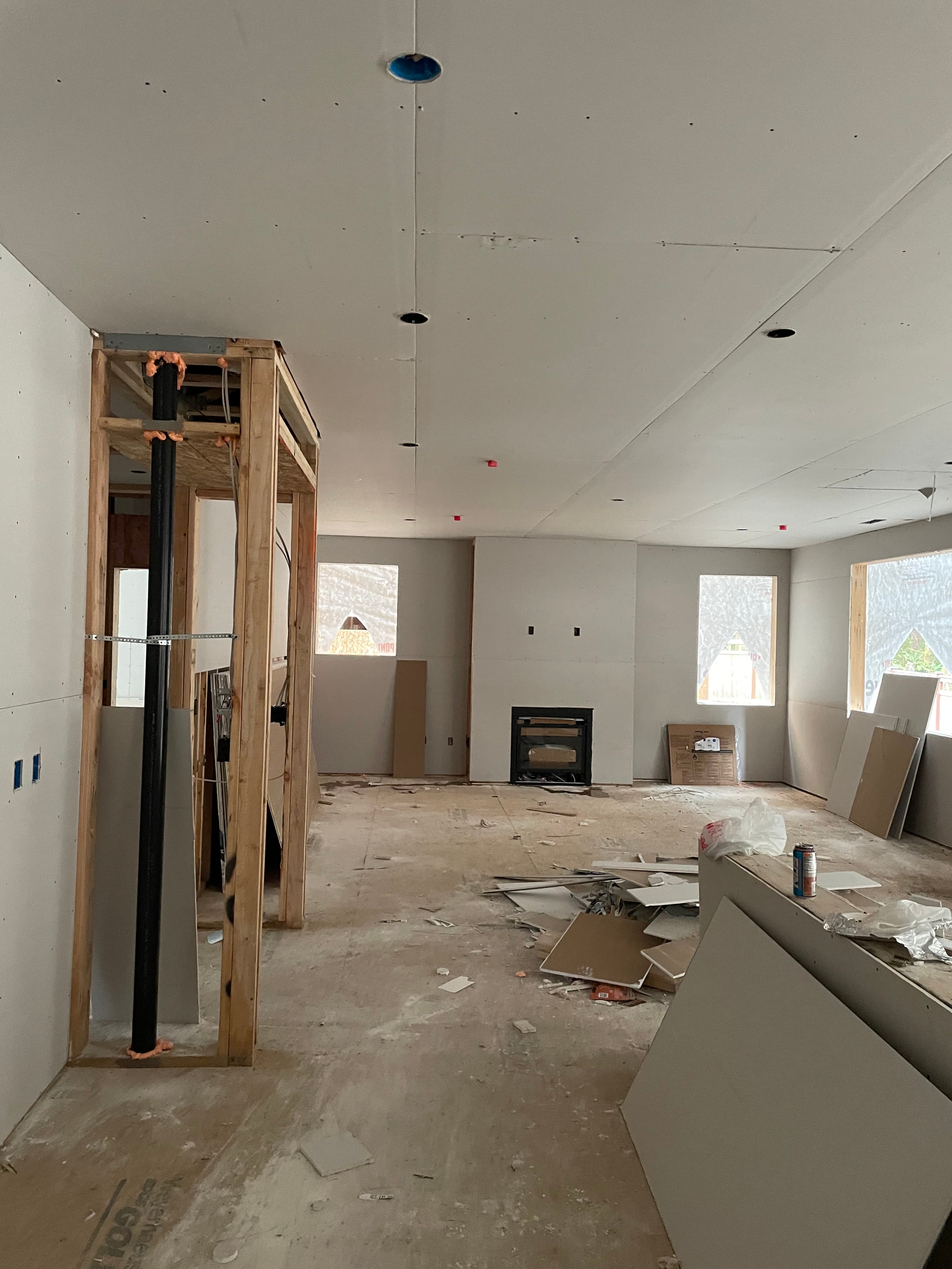 Interior room under construction with installed drywall, wooden framing, and debris on the floor.