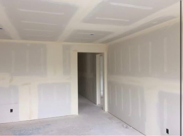 Newly installed drywall with taped and mudded seams in an unfinished room under construction.